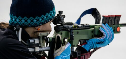 a woman with a hat and gloves holding a rifle